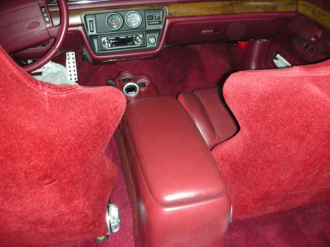 1992 Ford Crown Victoria - The interior of a car with plush red carpeting and matching red seats is shown, focusing on the center console and dashboard area. Visible…
