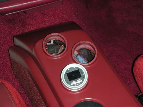 1992 Ford Crown Victoria - A close-up interior shot shows a red center console with two circular cutouts. One cutout contains wiring, and the other has a small blue o…