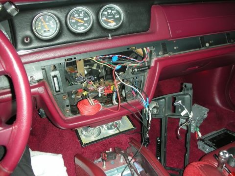 1992 Ford Crown Victoria - The interior of a car is shown with the dashboard disassembled, revealing wiring and gauges. A red steering wheel and red carpet are visibl…