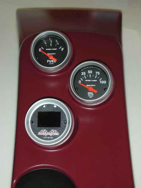 1992 Ford Crown Victoria - A close-up view of a dark red gauge cluster panel featuring a fuel level gauge, an oil pressure gauge, and a scan gauge. The gauges are all…