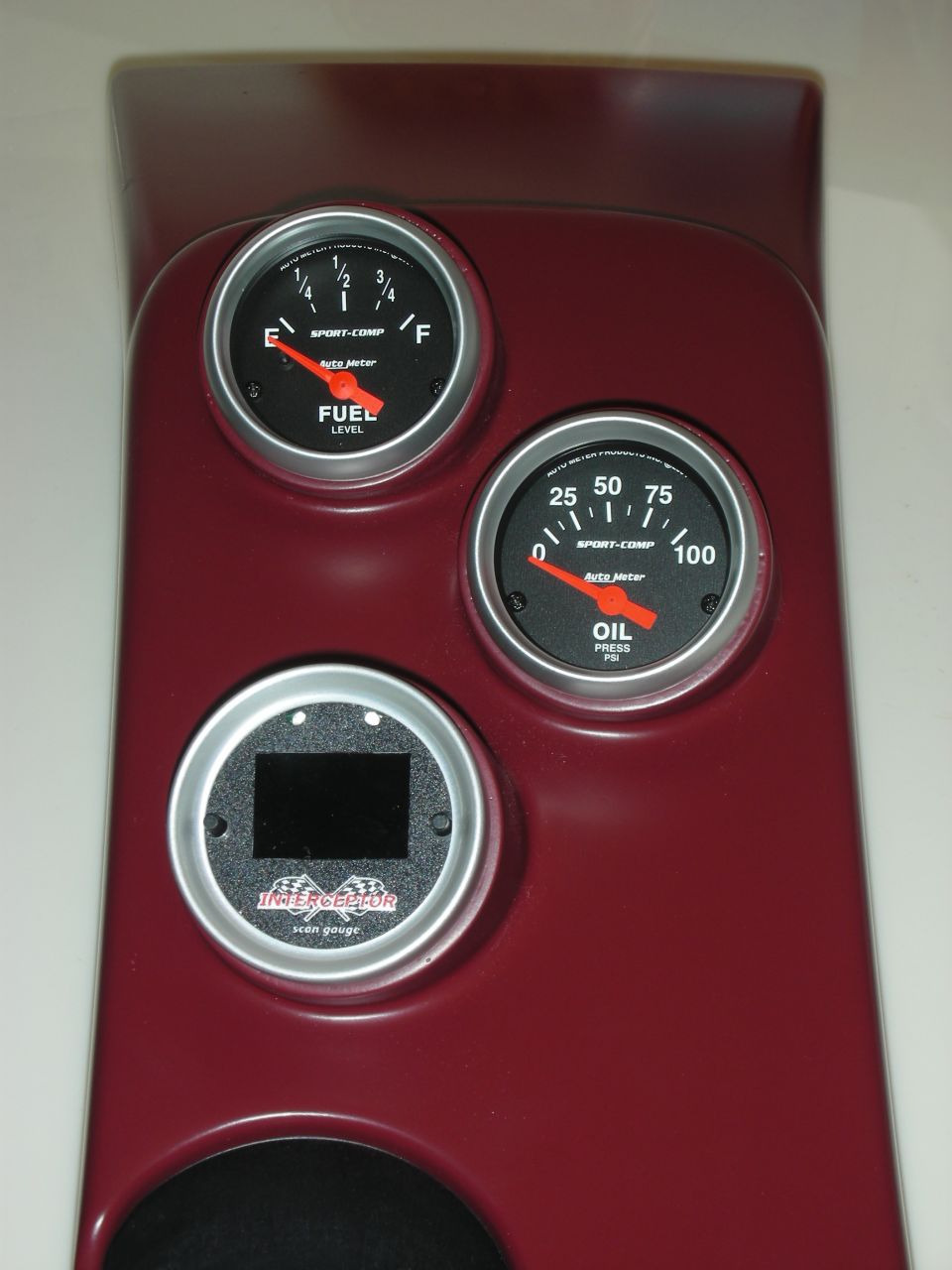 Dark red gauge cluster panel with fuel, oil pressure, and scan gauges.