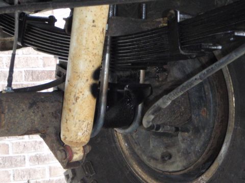1996 Ford Bronco - A close-up view of the rear suspension components of a 1996 Ford Bronco, showing the leaf springs, shock absorber, and part of the brake dr…