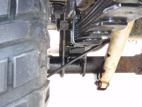 1996 Ford Bronco - A close-up view of the rear suspension of a 1996 Ford Bronco, showing the leaf springs, U-bolts, and a shock absorber. The tire tread is vi…