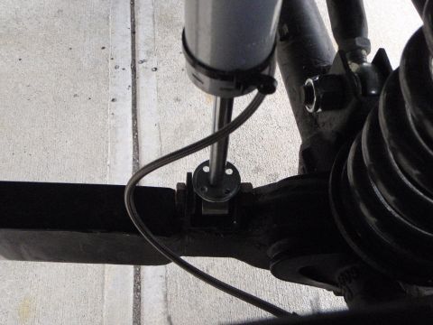 1996 Ford Bronco - A close-up view of the suspension system of a vehicle, showing a shock absorber, a spring, and various mounting hardware. The components ar…