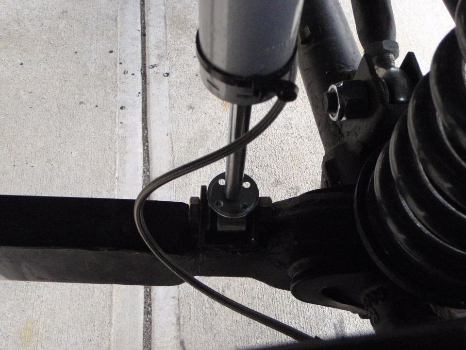 Vehicle suspension with shock absorber, spring, and mounting hardware on concrete.
