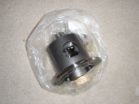 1996 Ford Bronco - A differential carrier is shown inside a clear plastic bag, resting on a carpeted surface. The differential carrier is dark gray with a sil…