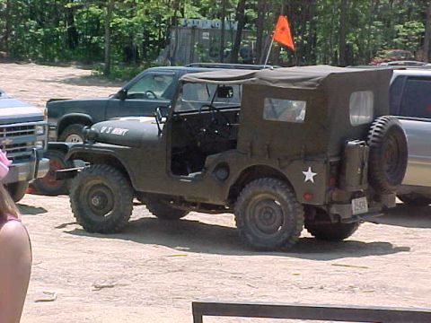 1993 Ford Bronco - An olive-drab military-style flat-fender Jeep with a soft top, doors off, "U.S. ARMY" lettering on the hood, a white star on the rear body…