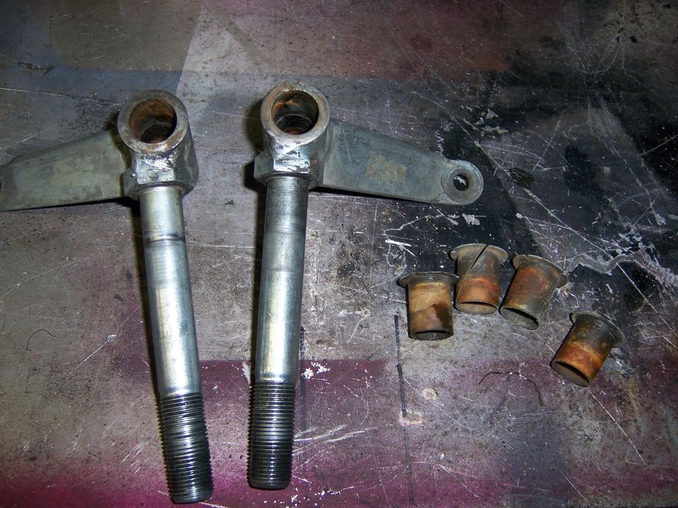 Two threaded spindle parts and four metal bushings on a workbench