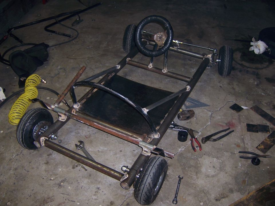 Photo of a go-kart chassis with mounted steering wheel and seat pan
