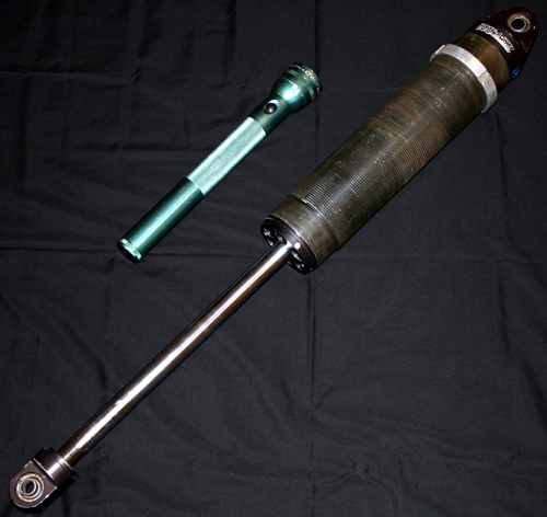 Green flashlight and a large shock absorber on a black background.