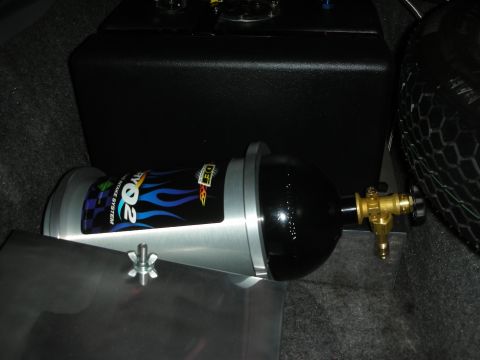 1992 Ford Crown Victoria - A nitrous oxide tank with blue flames and the text "RYO2" and "JET INTAKE SYSTEM" is mounted in the trunk of a vehicle next to a black stor…
