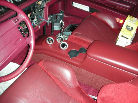 1992 Ford Crown Victoria - The interior of a classic Ford Crown Victoria shows a custom center console with aftermarket gauges and a cup holder, alongside the steerin…