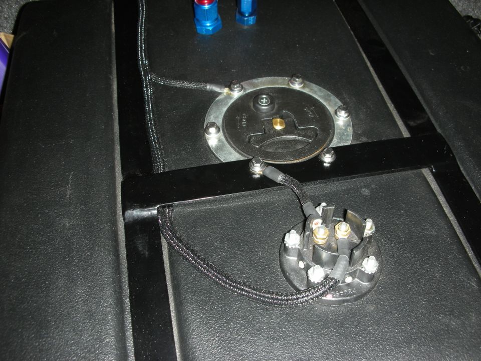 Fuel pump sending unit and wiring on a black textured surface.