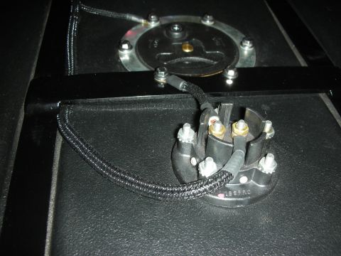 1992 Ford Crown Victoria - A close-up view shows a black electrical connector with brass terminals and silver bolts, connected to a fuel pump assembly. The connector…