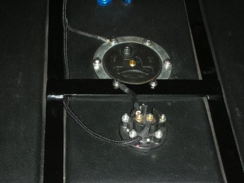 1992 Ford Crown Victoria - A close-up view shows two black fuel pump modules installed on a dark surface, connected by braided black hoses and wires. A black metal fr…