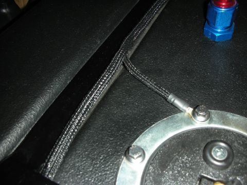 1992 Ford Crown Victoria - A close-up view shows a braided black hose with a heat-shrink-covered terminal attached to a metal ring secured by bolts. A blue and red fi…