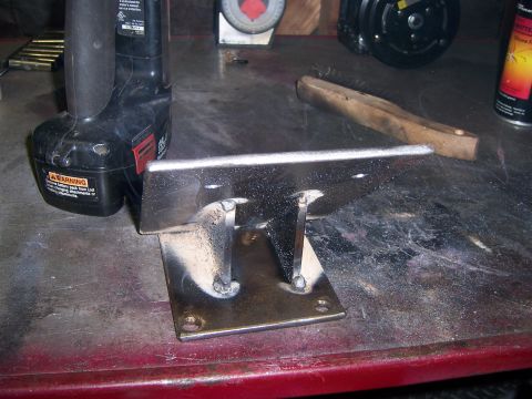 1991 Ford Bronco - Metal bracket welded together, sitting on a workbench with a drill nearby.
