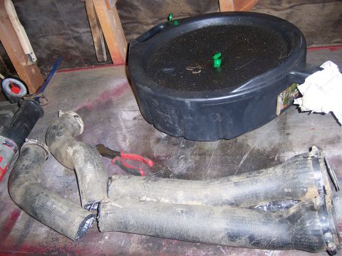 1991 Ford Bronco - Used radiator hoses and an oil drain pan are laid out on a surface, possibly for repair or disposal.