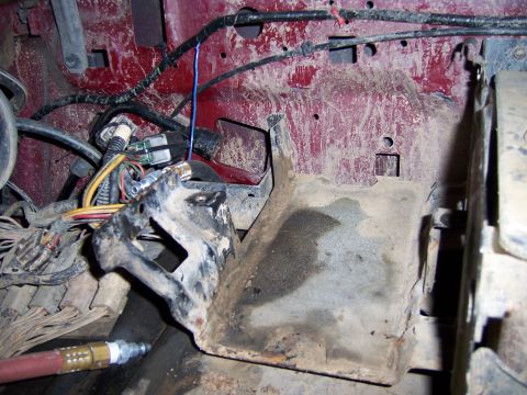 1991 Ford Bronco - Close-up view of the engine bay wiring and a metal bracket, showing red interior paint and some dirt.