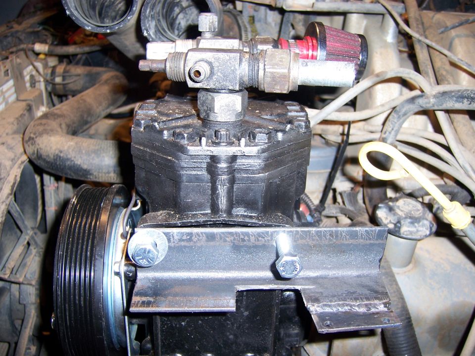 close-up of engine part with hoses and a small air filter