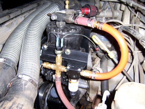1991 Ford Bronco - Aftermarket air compressor and plumbing installed in an engine bay.
