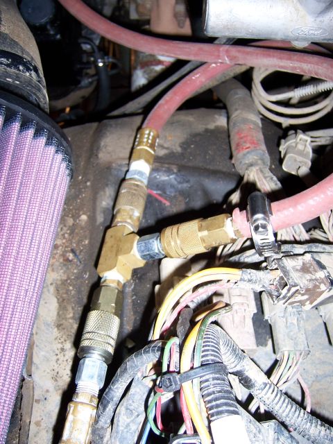 1991 Ford Bronco - Close-up view of engine components including an air intake and various hoses with quick-connect fittings.