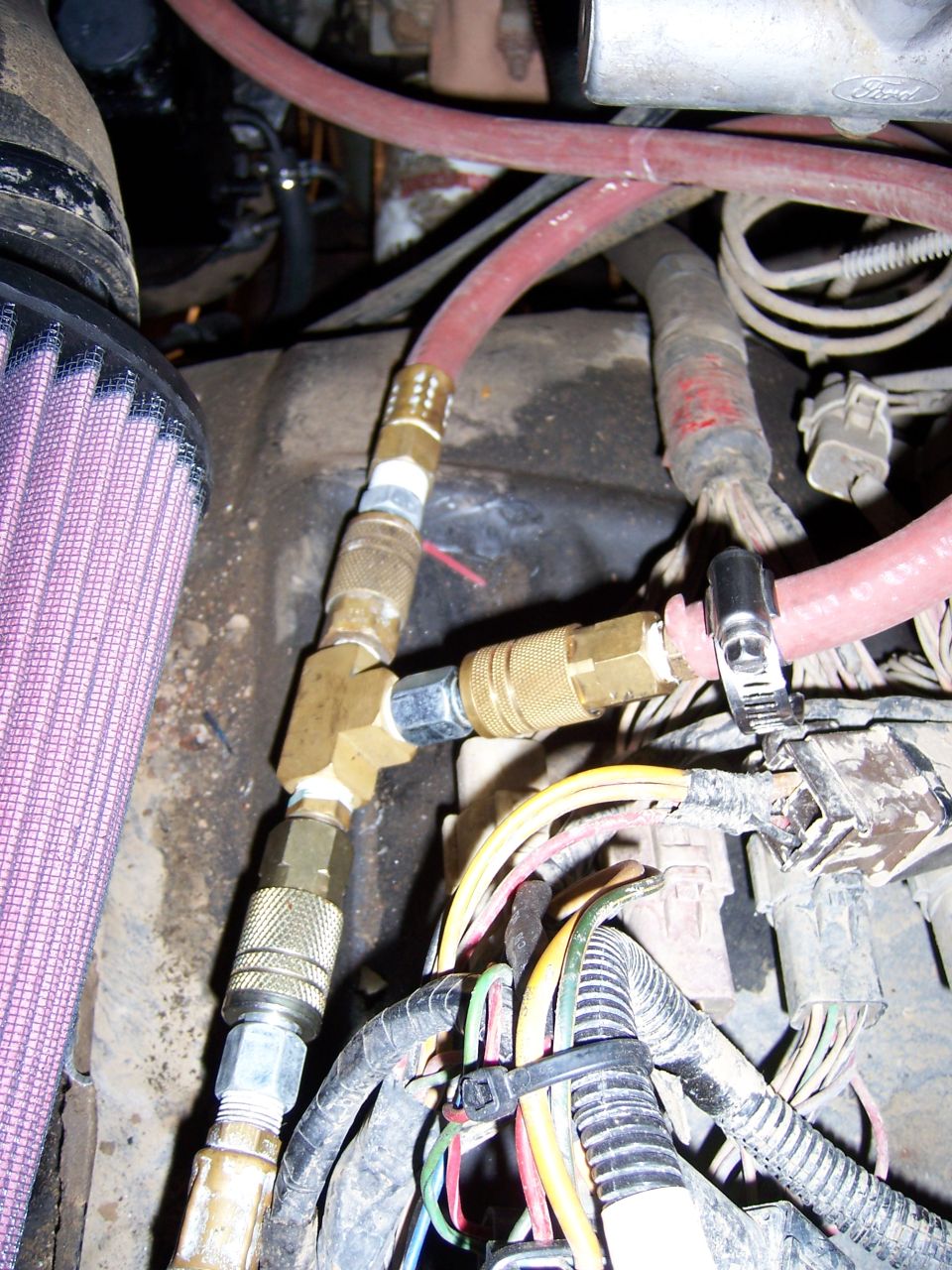 engine bay with purple air filter, red hoses, and brass fittings