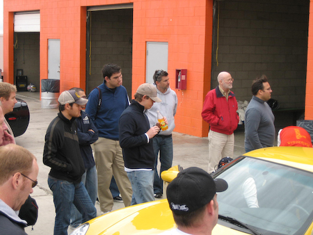 1993 Ford Taurus - A group of men stand around a yellow car in front of an orange building.