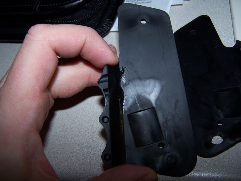 1986 Ford Bronco - A hand holds a black plastic part, possibly a component from a vehicle or other equipment.