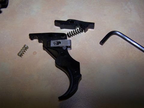 1986 Ford Bronco - Disassembled gun trigger mechanism with springs and an Allen wrench on a textured surface.