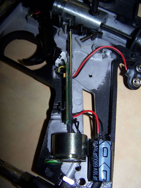 1986 Ford Bronco - Close-up view of the internal workings of a device, showing a trigger mechanism, motor, and a capacitor labeled 16V 6800uF.