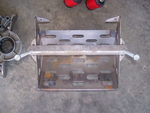 1990 Ford Mustang - Metal battery tray and engine component shown on a concrete surface.