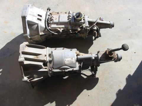 1993 Ford Taurus - Two automotive transmissions are shown side-by-side on a concrete surface. One transmission has a visible Tremec label.