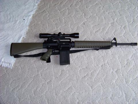 1995 Mercury Grand Marquis - An assault rifle with a scope and magazine is shown on a carpeted surface.