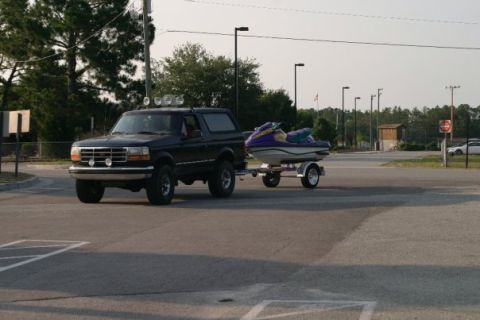 1981 Garelli Rally Sport - Black Ford Bronco towing a jet ski on a trailer on a sunny day.