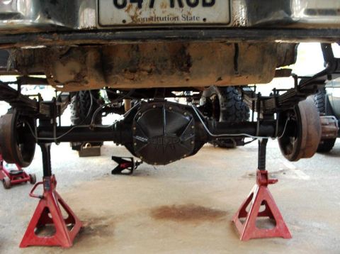 1990 Ford Bronco - The rear axle differential of a vehicle is shown while supported by red jack stands.