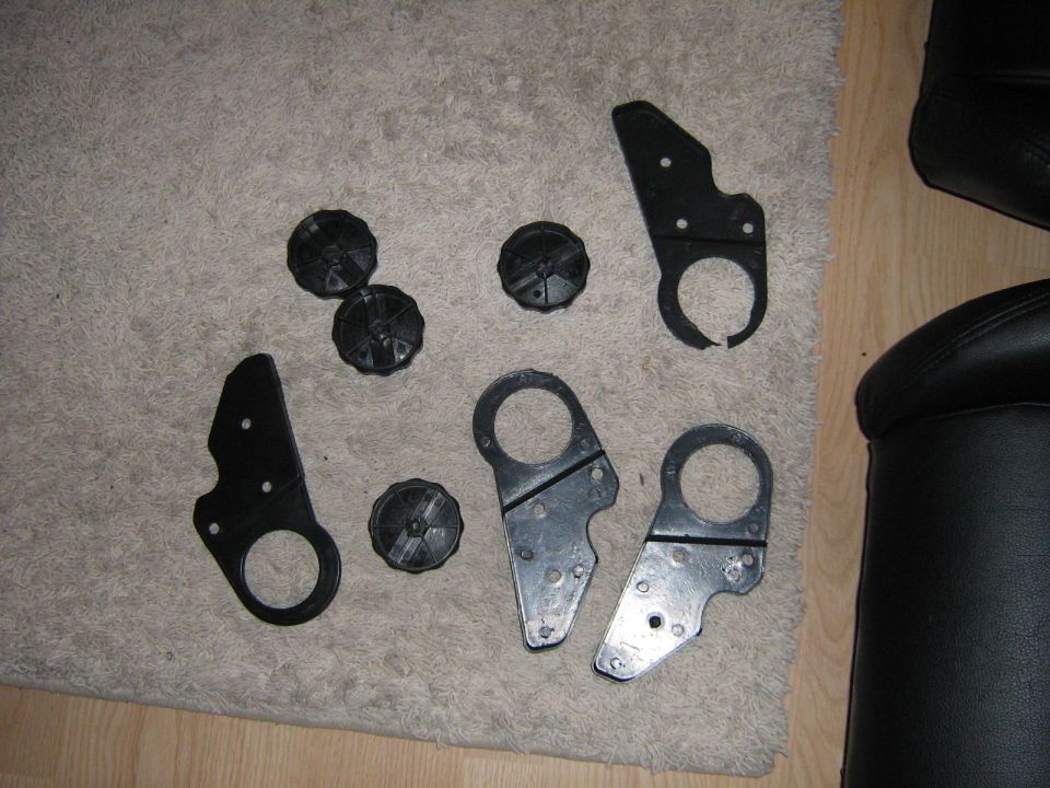 Several black plastic knobs and metal brackets laid out on a carpeted floor