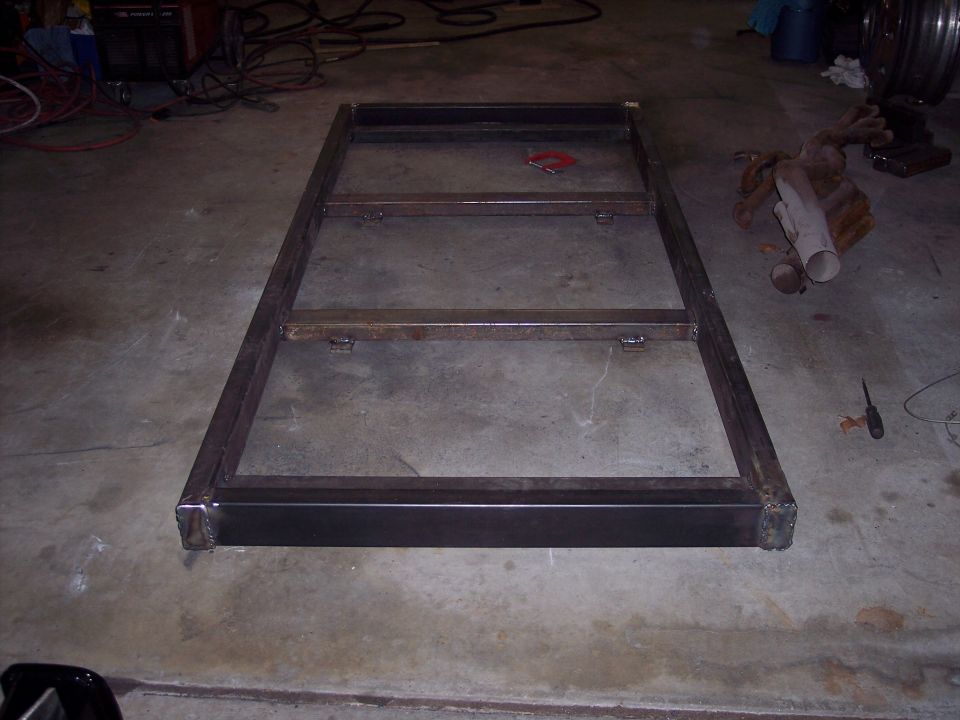 Rectangular metal frame with internal crossbars on a concrete floor