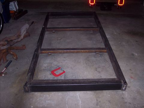 1981 Kenworth W900A - A metal frame is shown on a concrete floor, with a C-clamp resting on it.