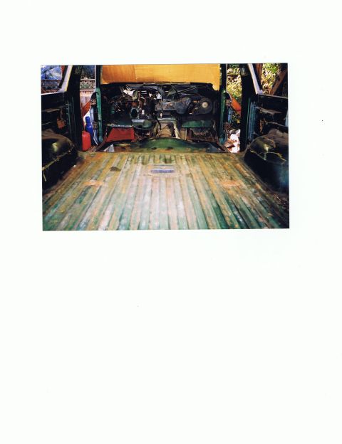 1978 Ford Bronco - The interior of a 1978 Ford Bronco shows its exposed engine and green-painted bed with wooden planks.