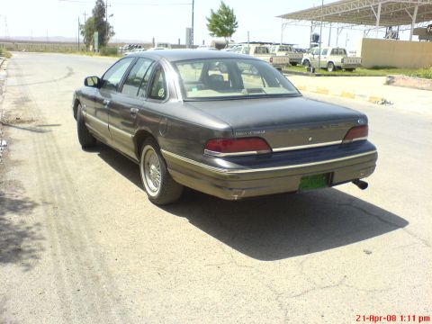 1992 Ford Crown Victoria - A 1992 Ford Crown Victoria LX sedan is parked on a dirt road, with other vehicles visible in the background.