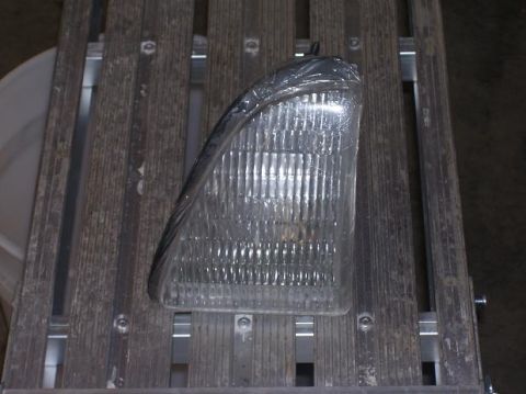 1991 Ford Bronco - Headlight assembly shown on a wooden surface with metal supports.