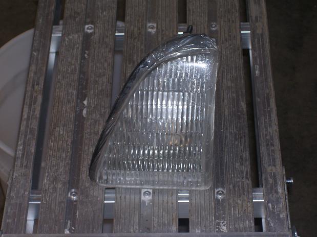 clear plastic headlight assembly with ribbed lens, wrapped in plastic