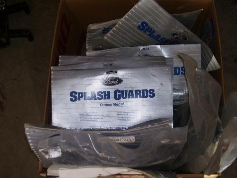 1991 Ford Bronco - Several Ford splash guards are neatly stacked inside a cardboard box, ready for installation.
