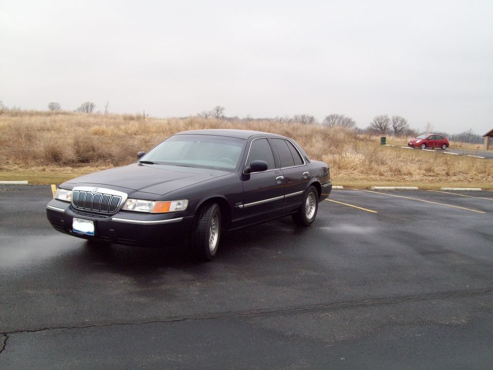 1999 Mercury Grand Marquis parked on wet asphalt, another car in background