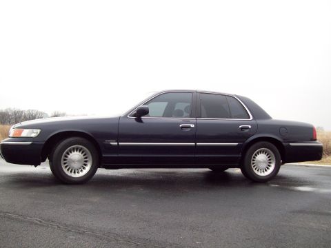 1999 Mercury Grand Marquis - A dark blue 1999 Mercury Grand Marquis is shown from the side on a wet asphalt surface.