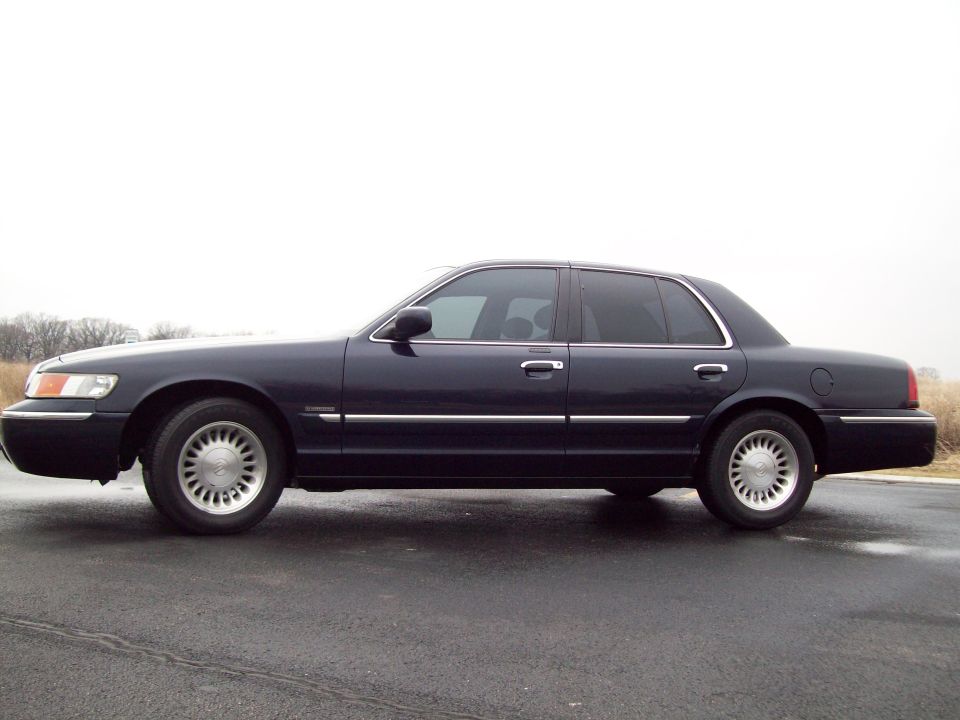 Side view of a 1999 Mercury Grand Marquis parked on a wet road
