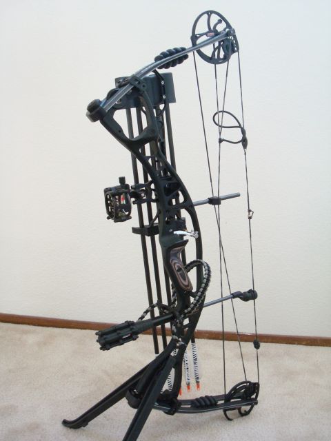 1990 Ford Bronco - A black compound bow is displayed on a stand, with its various components clearly visible.