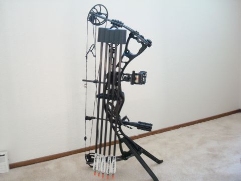 1990 Ford Bronco - A compound bow with a quiver of arrows is displayed on a stand against a white wall.