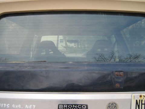1990 Ford Bronco - Rear view of a 1990 Ford Bronco, with a reflection of a house visible in the window.